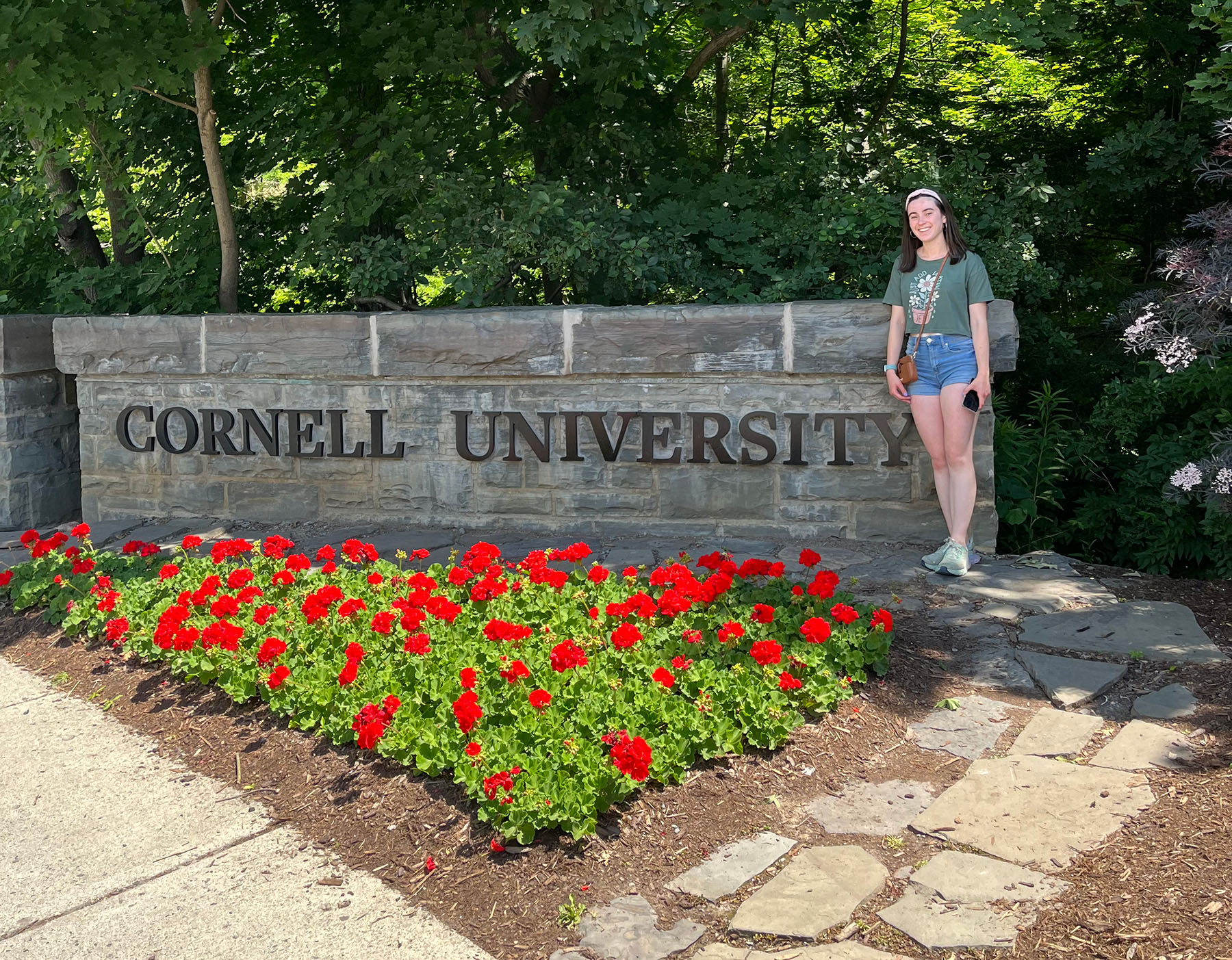 Student beside a sign that reads Cornell University