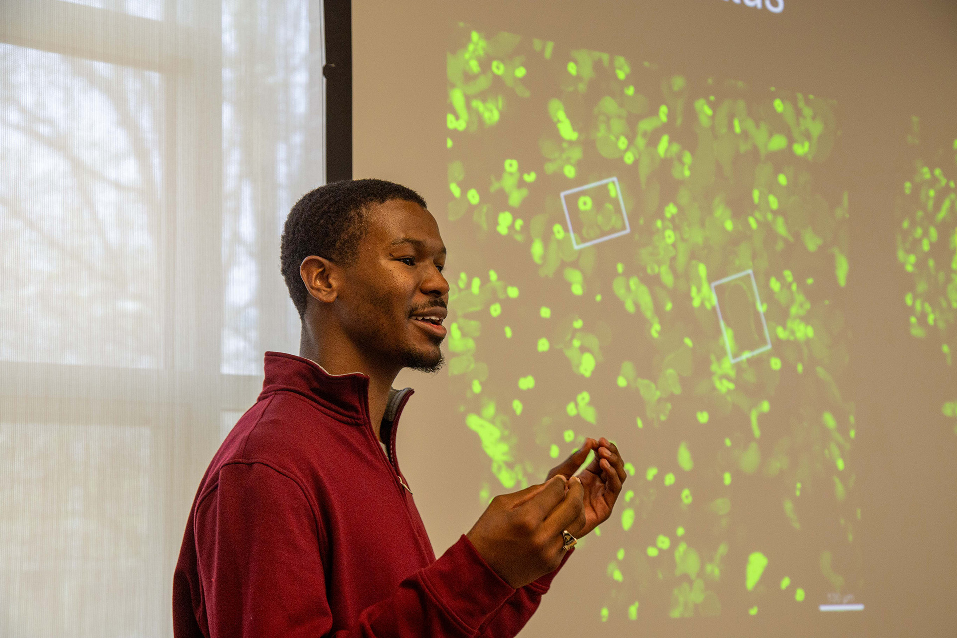 A man presents a slide with a microscopic image of a cell