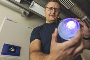 a man in a blue shirt holds up a grow light