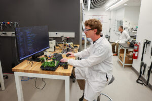 a scientist in a lab coatprograms a computer to interact with a plant